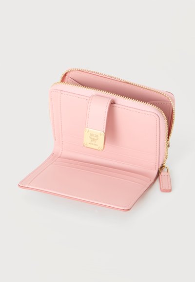 Portefeuille en cuir rose clair ouvert montrant des emplacements pour cartes et un compartiment zippé avec fermeture éclair dorée et plaque logo de la marque à l'intérieur.