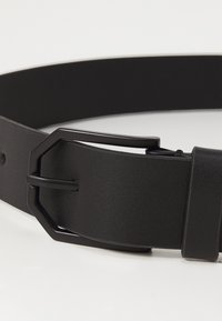 Cinturón de cuero negro con un acabado texturizado, que presenta una hebilla hexagonal negra mate y un detalle de lengüeta para un cierre seguro.