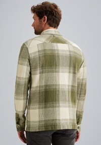 Groene en crèmekleurige geruite blouse van een gestructureerde stof, met knoopmanchetten en een achterpand. Kenmerkt zich door een ontspannen pasvorm en een kraag ontwerp.