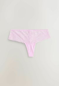 Világos rózsaszín csipke tanga virágmintákkal és hullámos szegéllyel, semleges hátteret lefektetve.