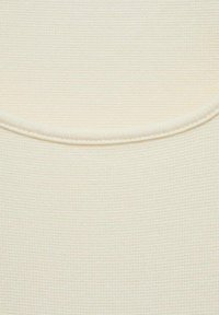 Textured cream-colored fabric featuring a fine grid pattern with a smooth, rounded neckline and subtle stitching along the edges.