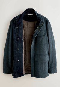 Dark blue herringbone jacket with a corduroy collar, zip and snap closure, and a brown quilted lining. Features front pocket and interior details.