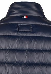 Marineblaue Steppjacke mit hohem Kragen, gestepptem Design, glatter Textur und einem kleinen dreifarbigen Etikett hinten.