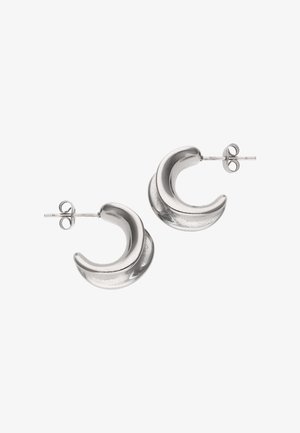 Små, tykke sølv hoop-øreringe med en unik buet halvmåneform og lukninger med stifter på hvid baggrund.