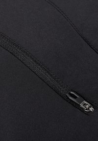 Svart tyg med en diagonal svart dragkedja, som visar texturerat dragkedjesnöre och en metallslidare med en plastdragning.