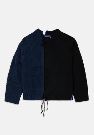 Knitted sweater with a split design; dark navy textured cable knit on one side, smooth black on the other, featuring a crew neckline and loose fit.