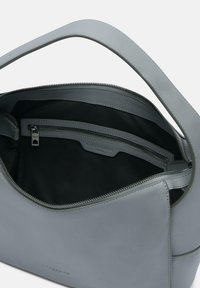 Szara skórzana torebka o gładkiej fakturze, z zamkiem błyskawicznym i wewnętrzną kieszenią. Posiada pojedynczy pasek do noszenia.