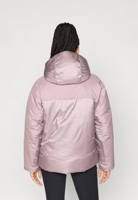 Giacca imbottita in lavanda chiaro con colletto alto e grande cappuccio. Presenta una texture liscia e lucida e un sottile dettaglio di cucitura sul retro.