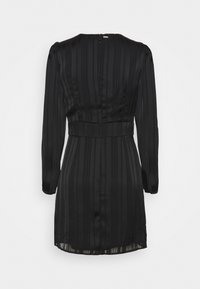 Robe noire à manches longues, coupe structurée et texture rayée. Elle possède une fermeture éclair à l'arrière et une ceinture à la taille pour souligner la silhouette.