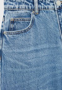 Vaqueros de denim azul claro con un diseño clásico de cinco bolsillos, costuras naranjas en contraste y detalles de botones metálicos en la cintura.