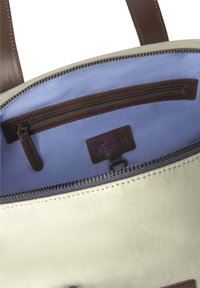 Borsa in tela color crema, con rifiniture in pelle marrone e tasca interna. Foderata in tessuto azzurro chiaro e con chiusura a zip.