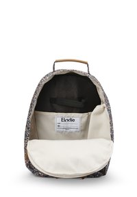 Barnryggsäck i mönstrad tyg med blommönster, tan detaljer och en vit insida med en etikett och förvaringsficka.