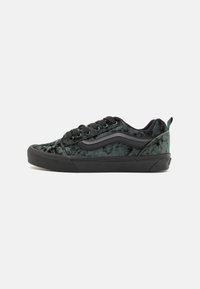 Adidași din catifea neagră cu o suprafață texturată, cusături albe, șireturi negre și o talpă din cauciuc. Prezintă un design clasic cu dungi pe lateral.