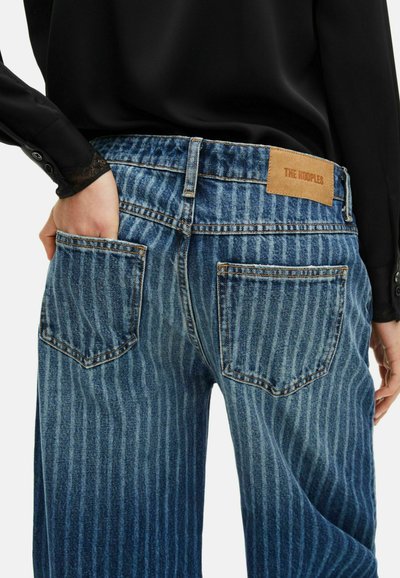 Niebieskie dżinsy z pionowym wzorem w paski, z brązową skórzaną naszywką na tylnej talii oraz kieszeniami po obu stronach.