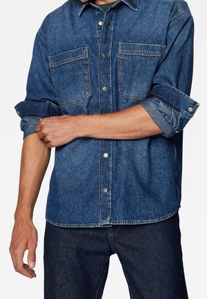 Dunkelblaus Denim Hemd mit durchgehender Knopfleiste, zwei Brusttaschen und hochgekrempelten Ärmeln. Verfügt über einen klassischen Kragen und eine legere Passform.