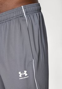 Grå trening shorts laget av lett stoff med elastisk midje, med hvite side-striper og en hvit logo på venstre bein.