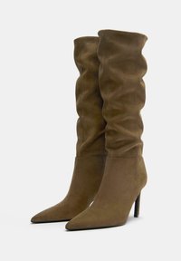 Bottes en daim marron montantes avec un design ample, un bout pointu et un talon stilettos. Tissu texturé avec des accents lisses.