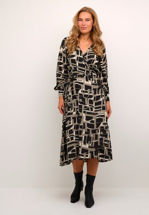 Rochie din țesătură cu mâneci lungi, în culori negre și bej, cu motive geometrice; are un design tip wrap, talie cu brâu și fustă fluidă. Botine negre până la gleznă.