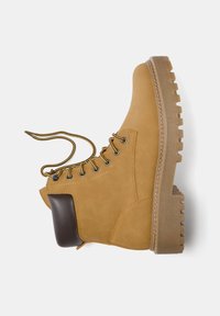 Stivale alla caviglia in suede beige con un accent in gomma marrone, caratterizzato da un design con lacci, suola testurizzata e punta rotonda.