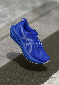 Niebieski but sportowy z przewiewną siateczką, teksturowanym wzorem oraz kontrastującą, jaśniejszą niebieską podeszwą, a także wyściełanym kołnierzem i sznurowadłami.