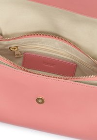 Ružová kožená kabelka s hladkou textúrou, obsahujúca vrecko so zipsom a vnútornú značkovú etiketu. Viditeľné sú zlaté kovanie.