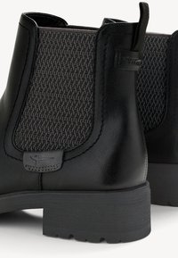 Bottes Chelsea en cuir noir avec panneaux latéraux élastiques texturés et languettes à l’arrière au-dessus des talons en caoutchouc épais.