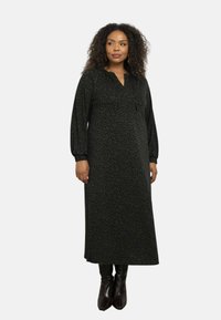 Dlouhé černé šaty s jemným zeleným abstraktním vzorem, s v-výstřihem a nařasenými dlouhými rukávy, vyrobené z měkké tkaniny.