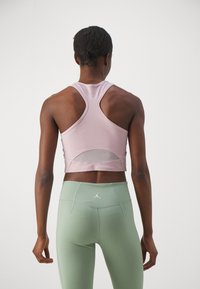 Lys rosa treningscrop topp med meshpanel, racerback design, kombinert med høyt oppkjørte mintgrønne leggings med logo bak.
