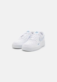 Vita Nike Air Force 1-sneakers med blå accenter. Har en slät läderstruktur, perforeringar på tån och en vadderad sula.