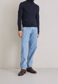 Námořnický rolák, světle modré džíny a tmavě hnědé vzorované kotníkové boty. Ležérní střih, s žebrovanými manžetami a páskem.