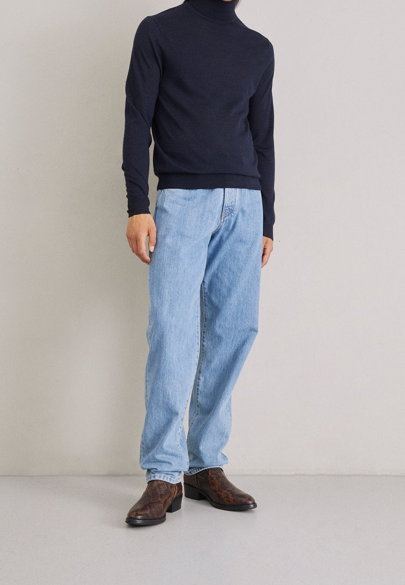 Námořnický rolák, světle modré džíny a tmavě hnědé vzorované kotníkové boty. Ležérní střih, s žebrovanými manžetami a páskem.