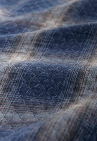 Textil kék és szürke kockás mintával, finom gyémánttextúrával. Puha anyag, különböző színű fonalak keverékével.