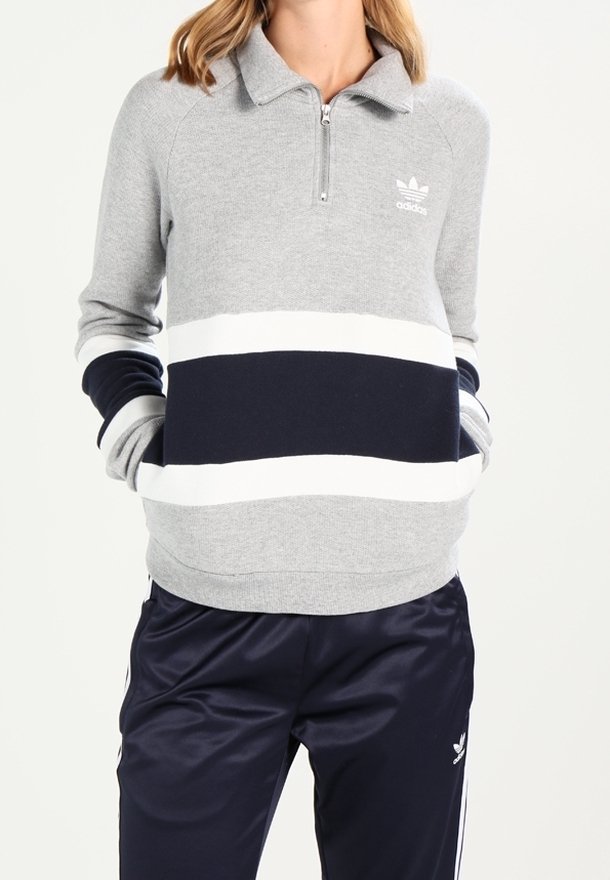 Grå zip-up huvtröja med marinblå och vita horisontella ränder. Har en krage och Adidas-logotypen på vänster bröst.
