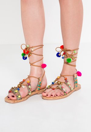 Platte sandalen gemaakt van tan leder, met kleurrijke kralen, pompons en enkelbandjes. Open teen ontwerp met een textuursjieke kurkzool.