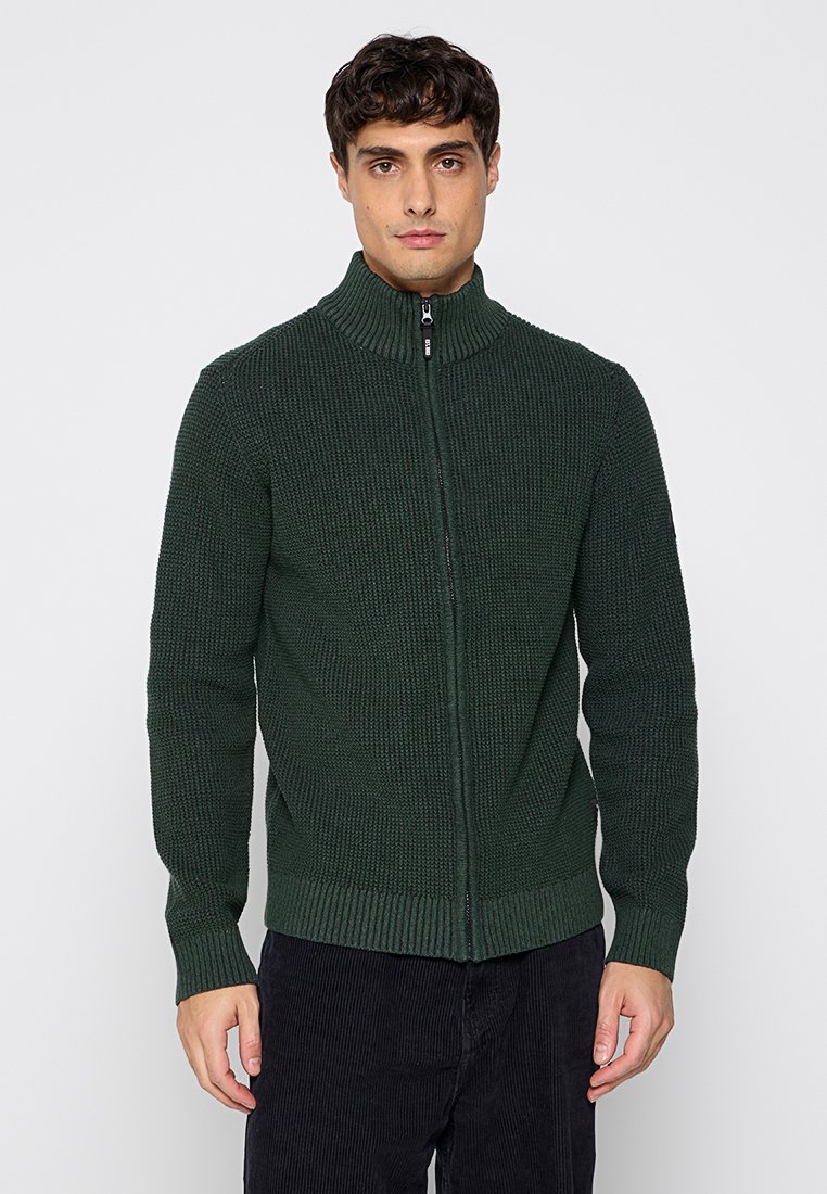 Ciemnozielony sweter z zamkiem błyskawicznym, o wysokim kołnierzu, z teksturowanym wzorem oraz ściągaczami na mankietach i dołem. Materiał ma strukturalny wygląd.
