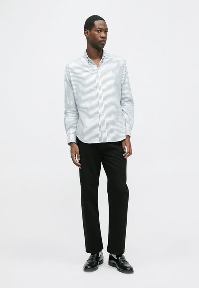 Valge ja sinise triibuga nööpidega särk, pikkade varrukatega, krae ja mustade pükstega ning mustade kingadega. Lihtne ja täpselt sobiv disain.