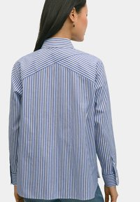 Gestreepte button-up shirt met blauwe en witte verticale strepen, lange mouwen, een puntige kraag en een ontwerpdetail met een achterpand.