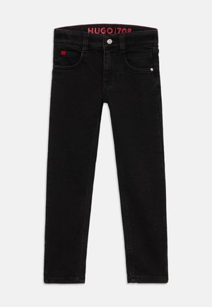 Črne denim jeans hlače z ozkim krojem, petimi žepi in kovinsko strojno opremo. Pas je opremljen z rdečo oznako za blagovno znamko.