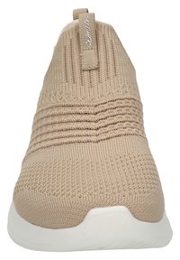 Zapatilla deslizante beige con parte superior de punto texturizado, diseño acanalado y suela blanca. Cuenta con una pestaña en el talón para facilitar el uso y el desuso.