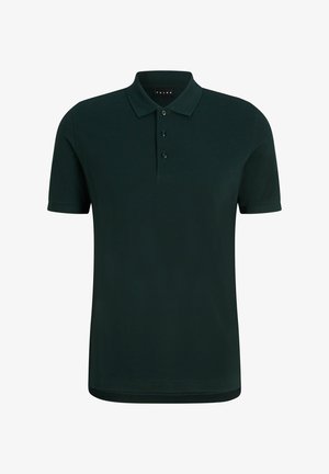 Ciemnozielona koszulka polo z krótkimi rękawami i trzema guzikami, w zestawie z czarnymi zwężanymi spodniami i czarnymi trampkami.