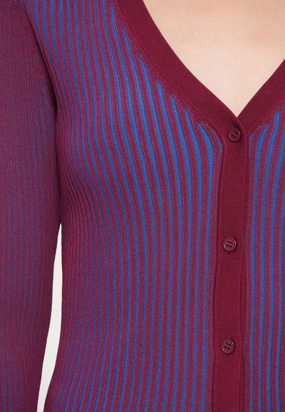 V-hals, knapped cardigan i maroon med horisontale blå striper. Ribbete tekstur, med fem knapper langs fronten for lukking.