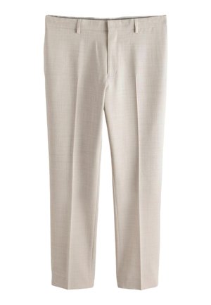 Béžové nohavice na mieru so slučkami na opasok, predným zipsom a vyžehlenými záhybmi pozdĺž rovnakých nohavíc.