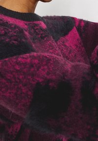 Suéter de punto difuso en tonos de magenta y negro, con cuello redondo y un patrón texturizado con densidad variable en toda la tela.