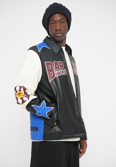 Schwarze Lederjacke mit mehrfarbigen Akzenten, einschließlich blauer Sterne und einer verspielten Grafik am Ärmel. Mit Reißverschluss vorne, lässige Passform.