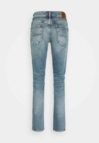 Blå denimjeans med rakt ben, femficksdesign och en läderetikett på midjan. Ljus tvätt med lätt blekning.