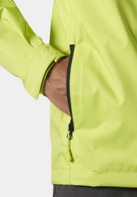 Chaqueta impermeable amarilla brillante con un bolsillo con cremallera y puños ajustables. Textura suave y diseño ajustado para mayor comodidad y facilidad de movimiento.