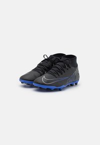 Scarpe da calcio nere con tomaia testurizzata, suola blu e logo bianco a contrasto. Design mid-top con lacci e tacchetti moldati per una buona aderenza.