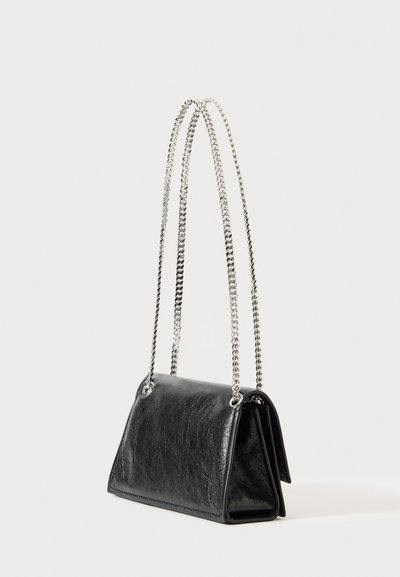 Μαύρη δερμάτινη τσάντα χεριού με ορθογώνιο σχήμα και μακριές ασημένιες αλυσίδες, τοποθετημένη όρθια σε λευκό φόντο.