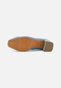 Chaussure plate en tissu bleu avec un bout rond, un petit talon et une semelle en caoutchouc marron. Le dessous montre une texture grainée et un petit numéro de taille.