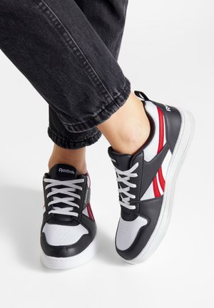 Mustvalged ja valged tennisekingad punaste triipudega, sujuva nahast pealispinnaga, valgete paeltega ja pehmendatud tallaga. Reebok'i bränding keele peal.